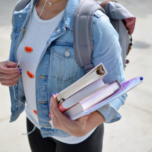 women with jean jacket holding books